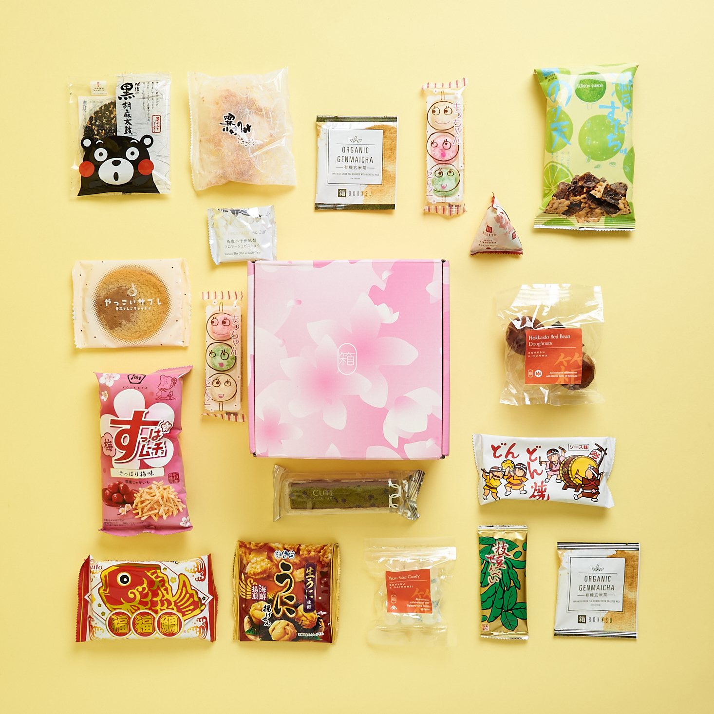 A female subscriber holding a floral cookie in front of green tea from her Bokksu delivery.