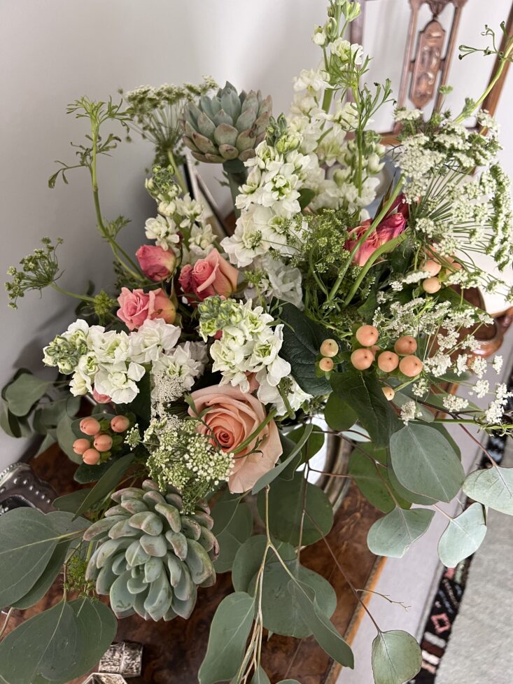 The Deluxe Poetic Bouquet features roses, hydrangea, and eucalyptus.