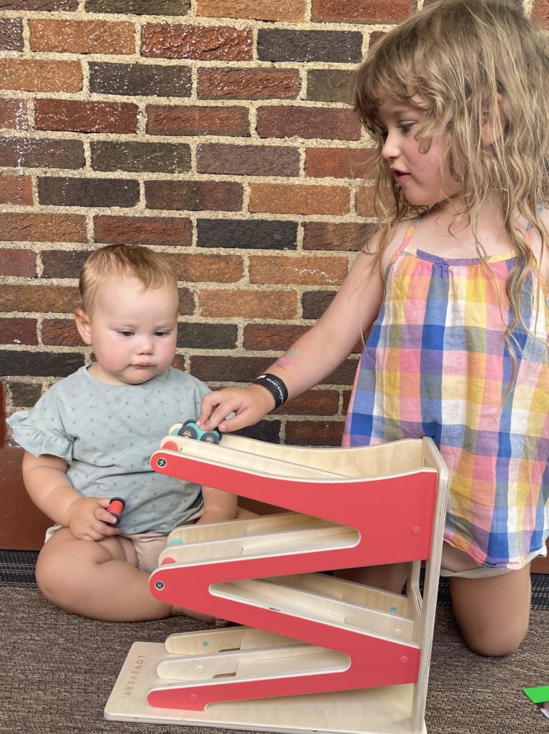 Christen's daughters playing with the Race & Chase Ramp from The Adventurer Play Kit by Lovevery.