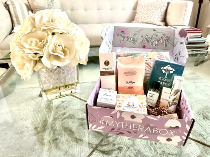 A monthly TheraBox box pictured next to an elegant feau floral arrangement.